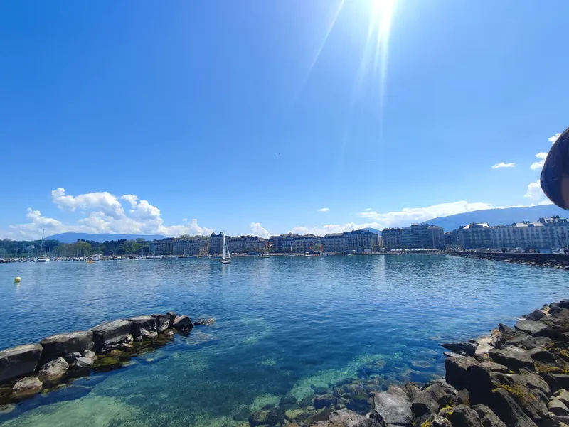 Digue de rochers sur un grand lac, ville et montagnes à l’horizon